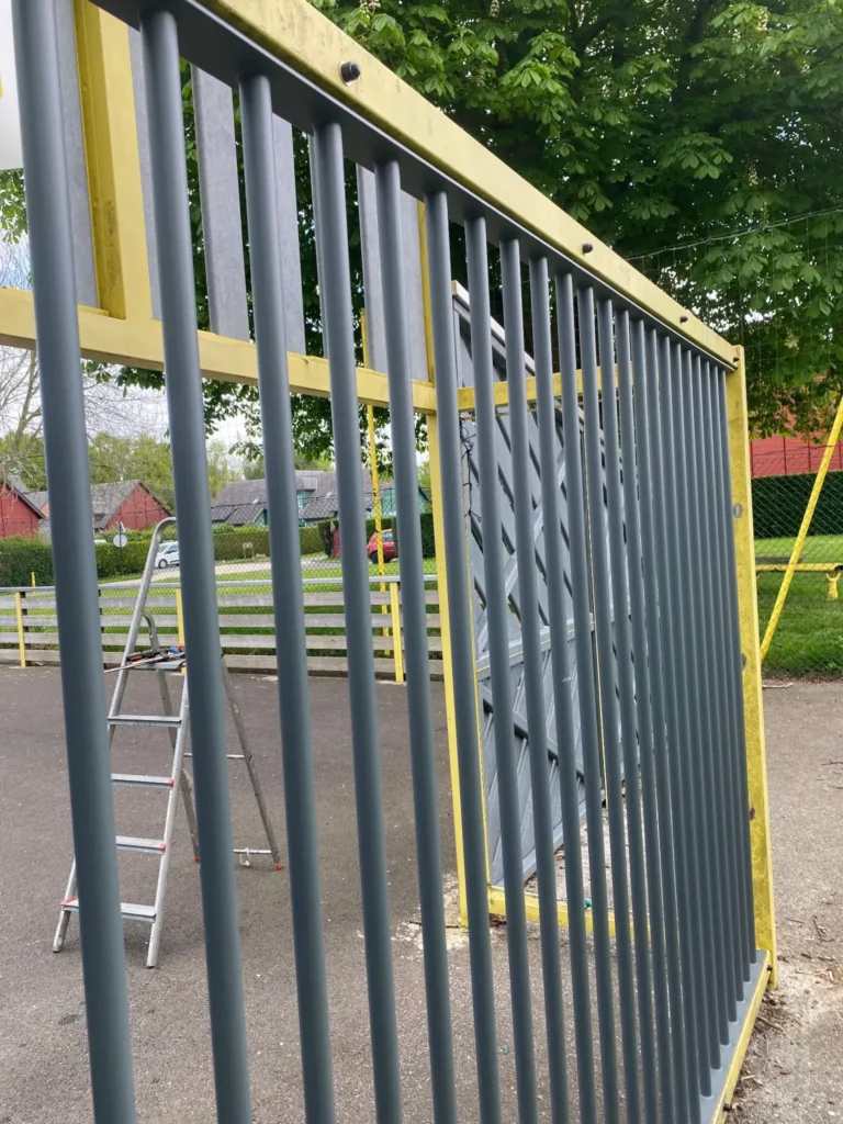 Portail métallique gris et jaune en extérieur